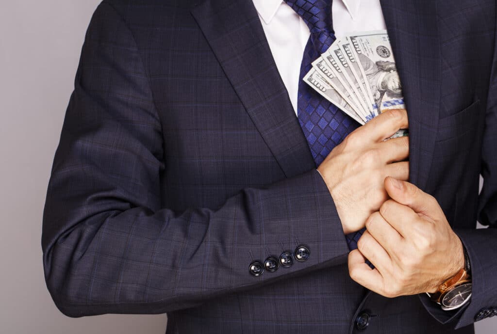 Businessman putting money in suit jacket pocket